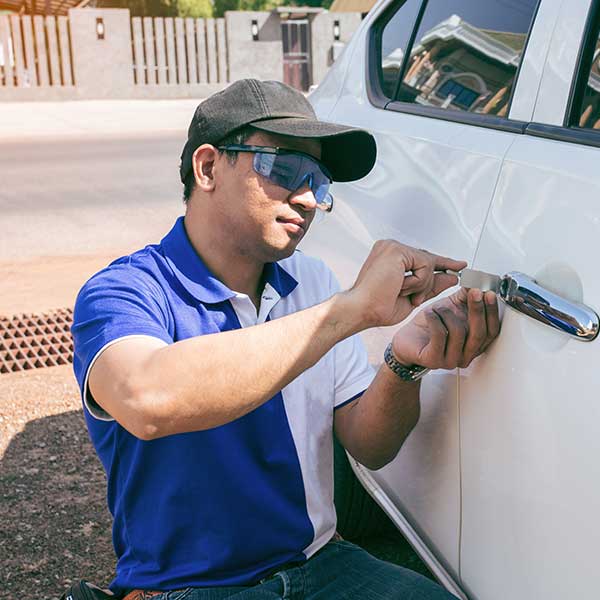 Young Man opening White Car with Lockpicker